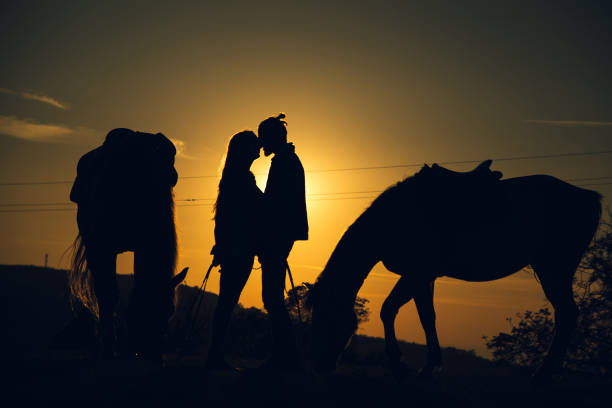 istock Couple kissing between two horses at sunset 1136800496