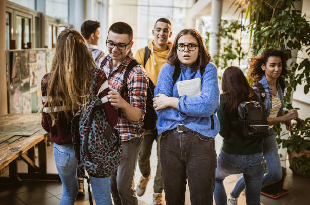 istock Fearful student among her classmates in a school hallway. 1136806129