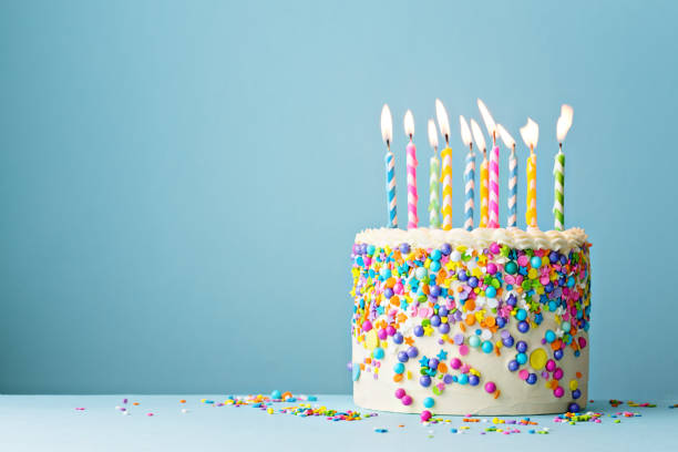 Birthday cake decorated with colorful sprinkles and ten candles Colorful birthday cake with sprinkles and ten candles on a blue background with copyspace happy birthday stock pictures, royalty-free photos & images