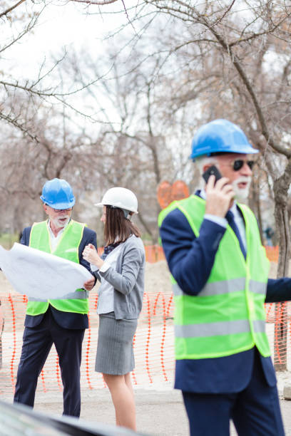 serious senior male and young female architects or business partners looking at building blueprints - 16707 imagens e fotografias de stock