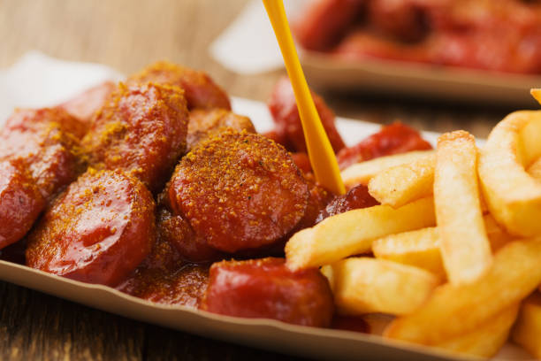 currywurst alemán tradicional, servido con patatas fritas en bandeja de papel desechable. - currywurst fotografías e imágenes de stock