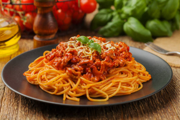 deliciosos espaguetis servidos en un plato negro - salsa de carne fotografías e imágenes de stock