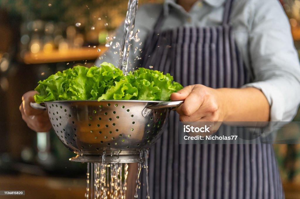 Rinsing salad Woman rinsing salad Lettuce Stock Photo