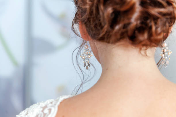 istock Wedding details and accessories. Bride putting pearl earring 1136815897
