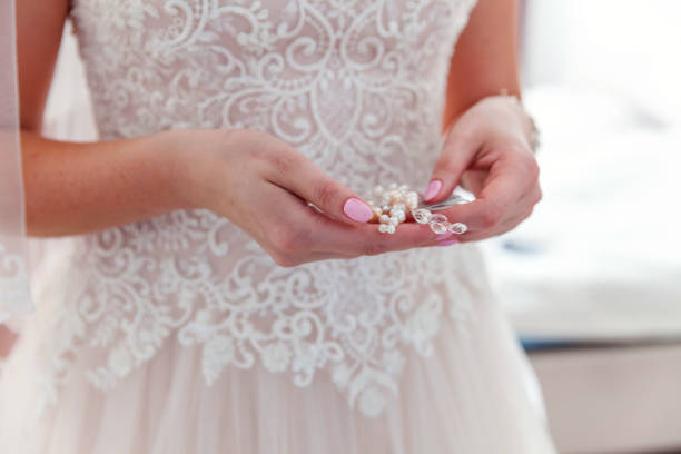 istock Wedding details and accessories. Bride putting pearl earring 1136815934