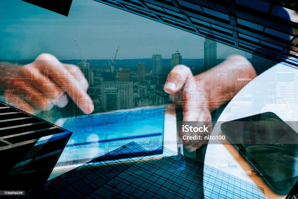 financial district and man using tablet a multiple exposure of a financial district and a man using a tablet, depicting the idea of the modern online banking concept or the modern business concept Electronic Banking Stock Photo