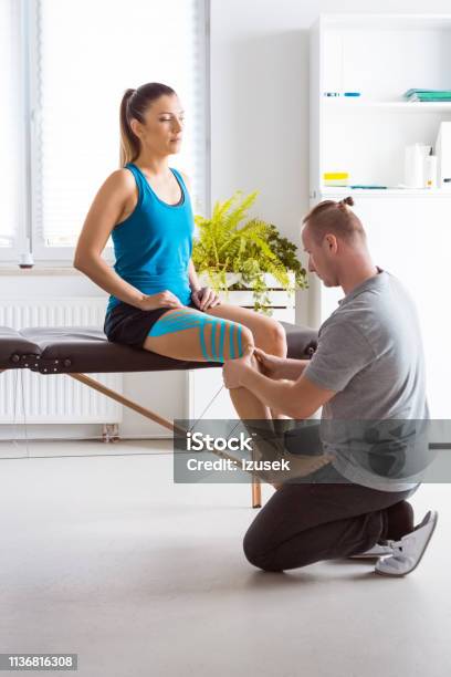 Physiotherapist Massaging Young Womans Leg Stock Photo - Download Image Now - Recovery, Adhesive Tape, Adult