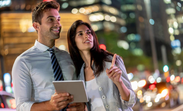 istock Happy couple using app on a tablet computer on the street at nighttime 1136817373
