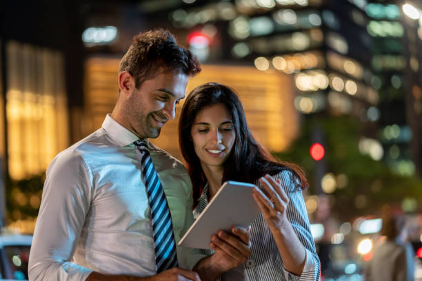 istock Business people using app on a tablet computer on the street at nighttime 1136817382