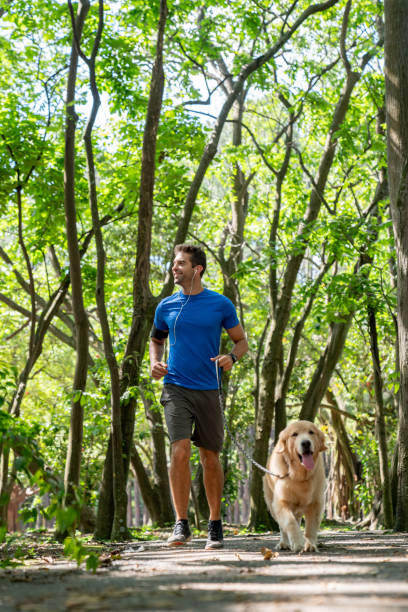 istock Athletic man running at the park with their dog 1136817447