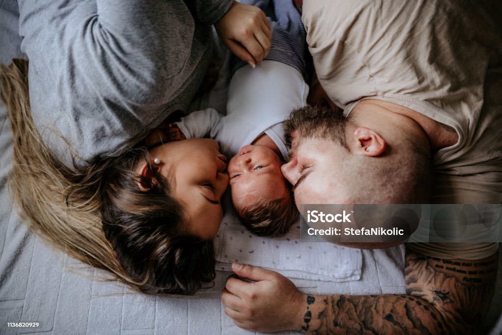 Lovely family enjoying day at home Family with one child laying on bed, enjoying day at home Parent Stock Photo