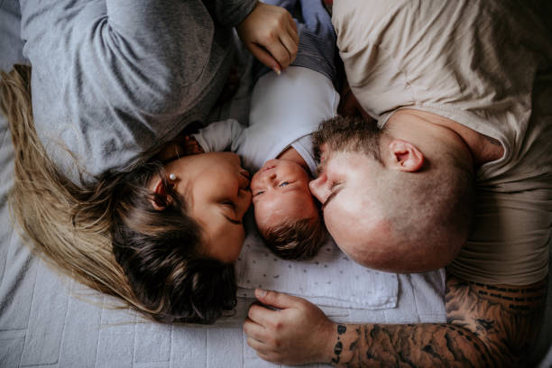 Lovely family enjoying day at home Family with one child laying on bed, enjoying day at home tattoo photos stock pictures, royalty-free photos & images