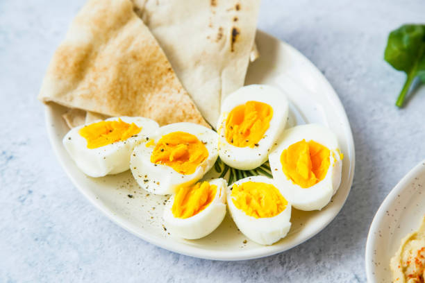 uova sode tagliate a metà condite con pepe e sale con pane pita su un piatto, pasto sano antipasti - hard cooked egg foto e immagini stock