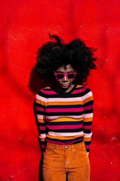 istock African woman standing on red bacground and looking down 1136823955
