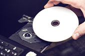 Male hand inserting a DVD into a disk drive. Software or drivers installation concept.