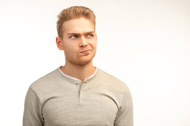 istock Discontent young businessman, purses lower lip, looks stressfully, feels dejected by negative announcement, models against white wall, blank space aside 1136829125
