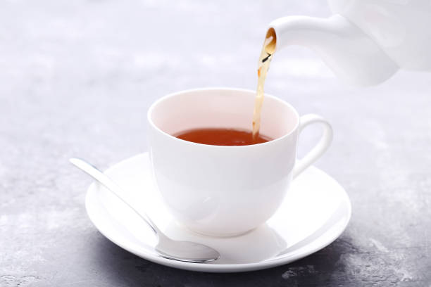 istock Pouring tea from teapot in white cup on wooden table 1136831083