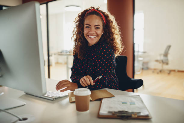 istock Smiling businesswoman sitting at her office workstation going over paperwork 1136831221