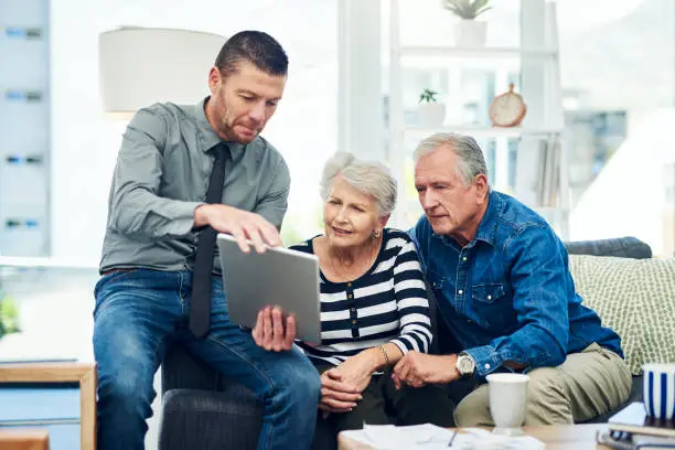 Shot of senior couple using a digital tablet during a consultation with a financial advisor at home