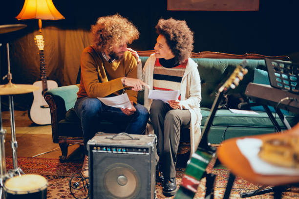 istock Couple looking at music notes while sitting on couch in home studio. 1136834434