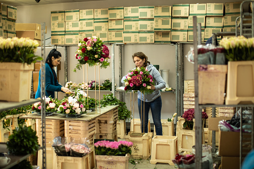 Two women working hard at flower shop, making flower arrangements together