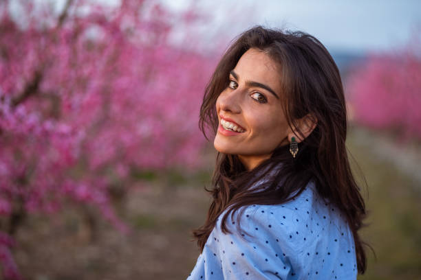 istock beautiful young woman peach tree blooming sunset smiling 1136836684