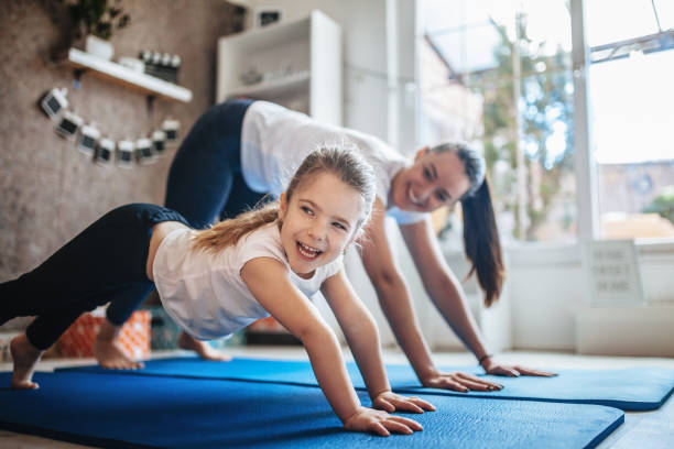 istock Mother and daughter working out together doing exercise at home 1136836695
