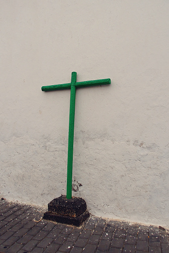 A simple green wooden cross on the street based on an old white house on the island of Lanzarote