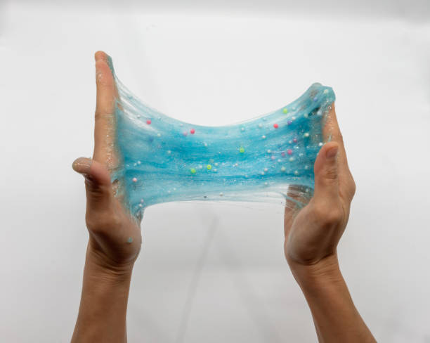 Hand strecthing transparent blue glitter slime isolated on white background stock photo