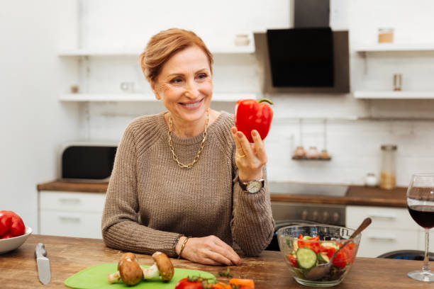 istock Beaming mature lady leaning on wooden table in kitchen 1136839696