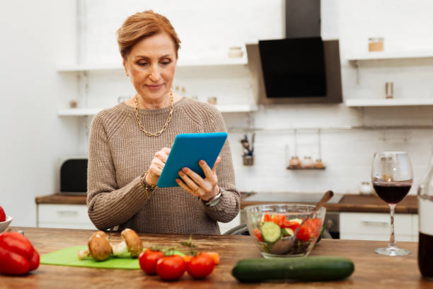 istock Attentive pleasant lady staying in kitchen and carrying her tablet 1136839718