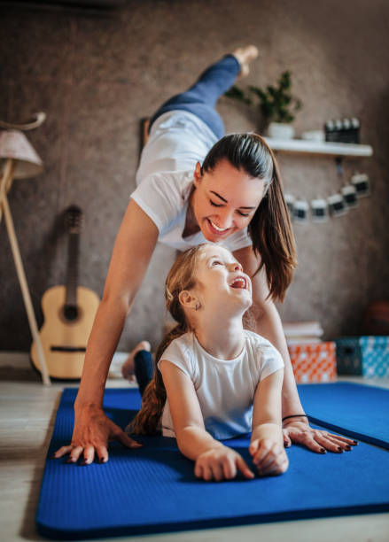 Mother and daughter working out together doing exercise at home Mother and daughter working out together doing exercise at home exercise room photos stock pictures, royalty-free photos & images