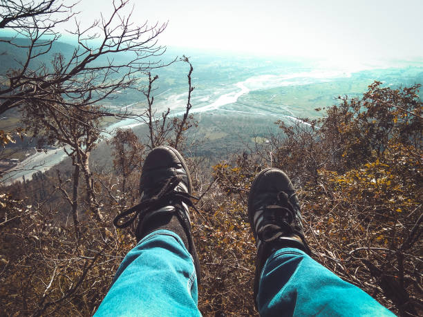 istock Man sitting on a mountain with hanging legs 1136841344