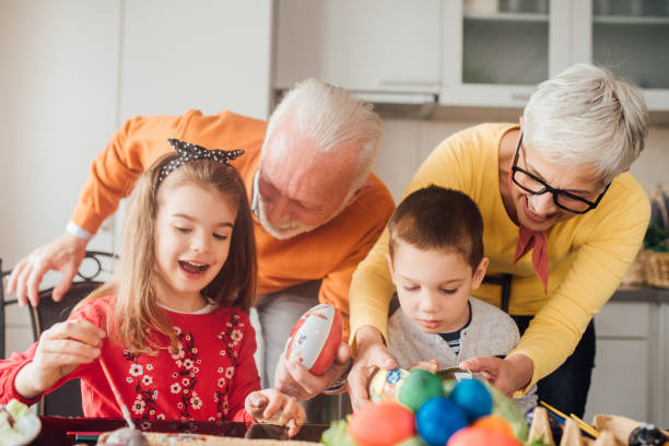istock Old couple helping children decorate Easter eggs 1136842838