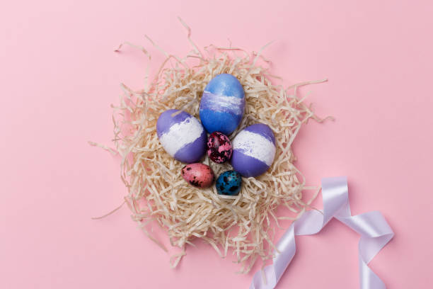 istock Easter eggs in nest with white ribbon on pink background. Easter texture 1136844623