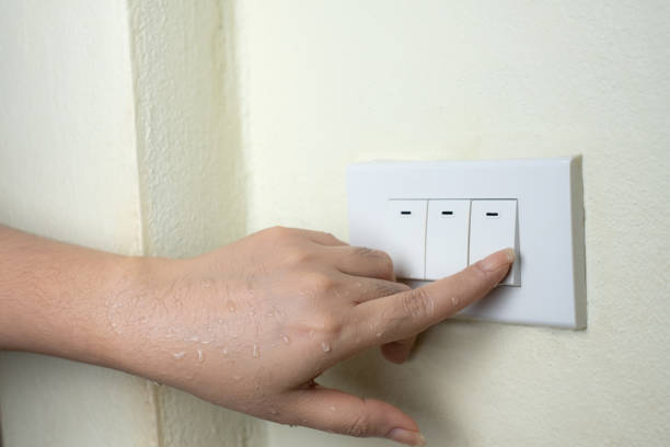 istock Wet hand turn on lights electric switch on white wall background, Do not turn the power off while moist hands may electric shock concept 1136845077