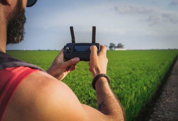 istock Bearded male model use drone remote control to fly device in air. Man operating drone flying in nature. New technologies and innovations concept. Green rice fields background. 1136846806