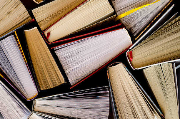 istock Lots of colourful thick open books stand on a dark background 1136848559
