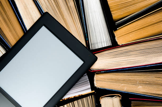 istock The e-book with a white screen lies on the open multi-colored books that lie on a dark background, close-up 1136848564