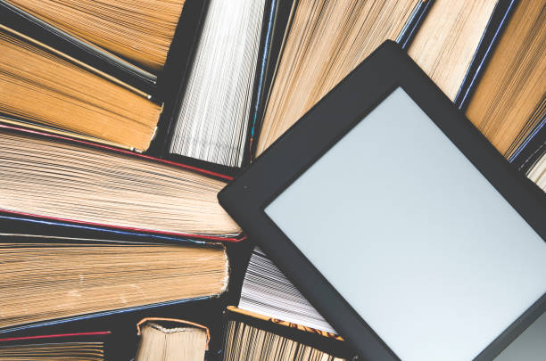 istock The e-book with a white screen lies on the open multi-colored books that lie on a dark background, close-up 1136848569