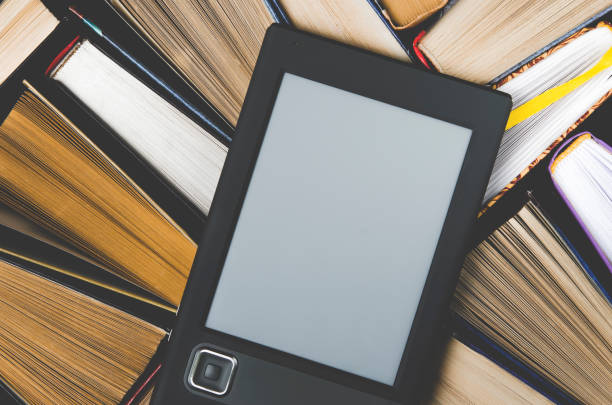 istock The e-book with a white screen lies on the open multi-colored books that lie on a dark background, close-up 1136848572