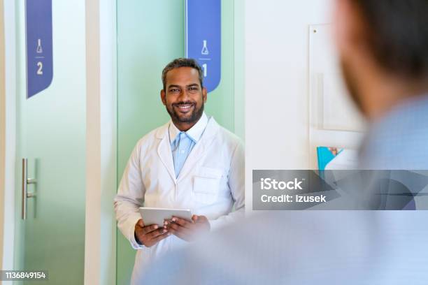 Smiling Male Doctor Looking At Patient In Corridor Stock Photo - Download Image Now - 30-34 Years, 35-39 Years, Adult