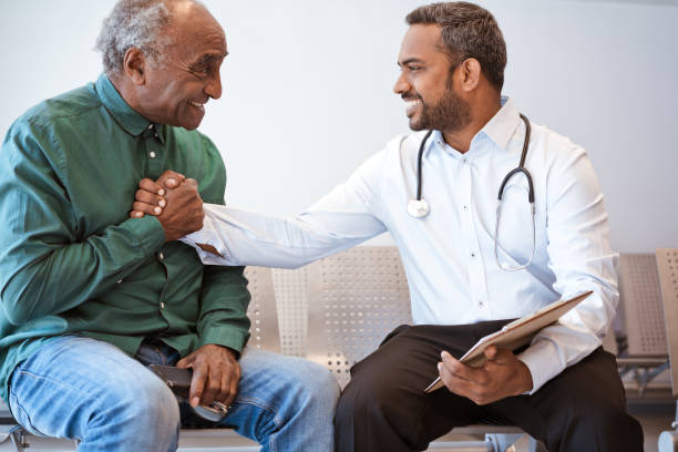 Excited senior man shaking hands with doctor Happy doctor giving good news to male patient in waiting room. Excited senior man is shaking hands with healthcare worker with clipboard. They are at hospital. good news stock pictures, royalty-free photos & images