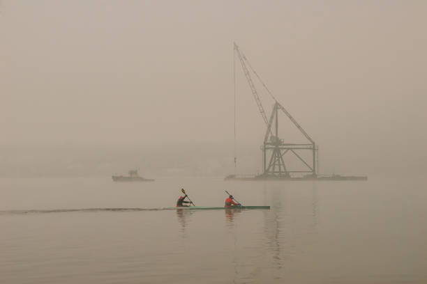 istock Two people on the kayak float towards the boat and the floating crane 1136852205