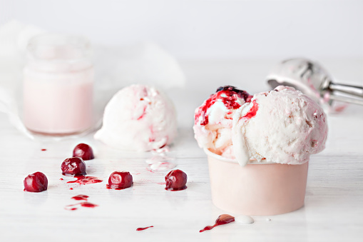Cherry yogurt Ice Cream in a paper cup with cherries