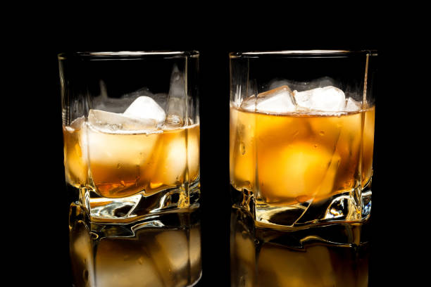 istock Whiskey with ice close up on a glass table isolated on a black background 1136855382