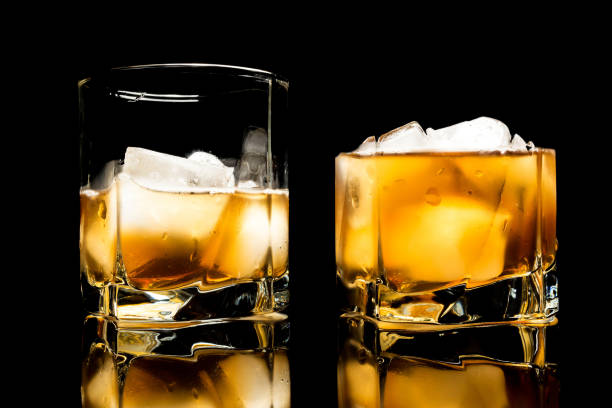 istock Whiskey with ice close up on a glass table isolated on a black background 1136855391