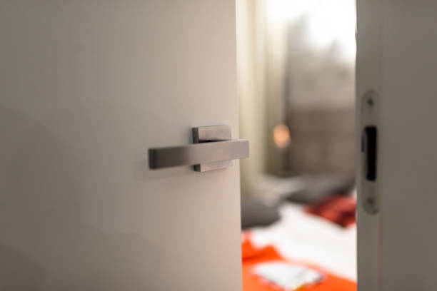 istock Ajar door to a modern bedroom with a light, visible blurred bed, bedding and orange pillows. 1136856709