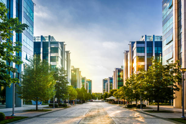 Buildings in office park at sunset Office buildings at sunset in the front of the blue sky with scattered clouds. The glass facade strongly reflects the sky and tree tops. architecture built structure futuristic contemporary stock pictures, royalty-free photos & images