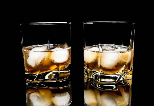 istock Whiskey with ice close up on a glass table isolated on a black background 1136858118